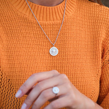 Laden Sie das Bild in den Galerie-Viewer, Damenanhänger „Kompassrose 2.0“ aus rhodiniertem 925er Silber mit Strandsand-Füllung an einer Silberkette, getragen zu einem orangefarbenen Strickpullover.