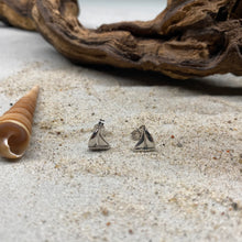 Laden Sie das Bild in den Galerie-Viewer, Ohrstecker "Ahoi" von DUR Schmuck, kleines Segelboot aus 925er Sterlingsilber, dekoriert auf Strandsand vor einem Stück Treibholz